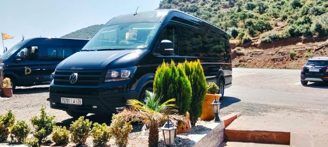 Minibus Volkswagen noir vu de face, stationné devant un paysage de montagne